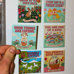 Hand holding the Good Things Are Coming / Stay Hopeful magnet in front of a white refrigerator displaying all six Spellbound Magnet Co. Easter 2026 Magnet Pack designs, including Grow at Your Own Pace, Every Day Is a Fresh Start, You Are One of a Kind, Let Yourself Be Joyful, and You Deserve Good Things.