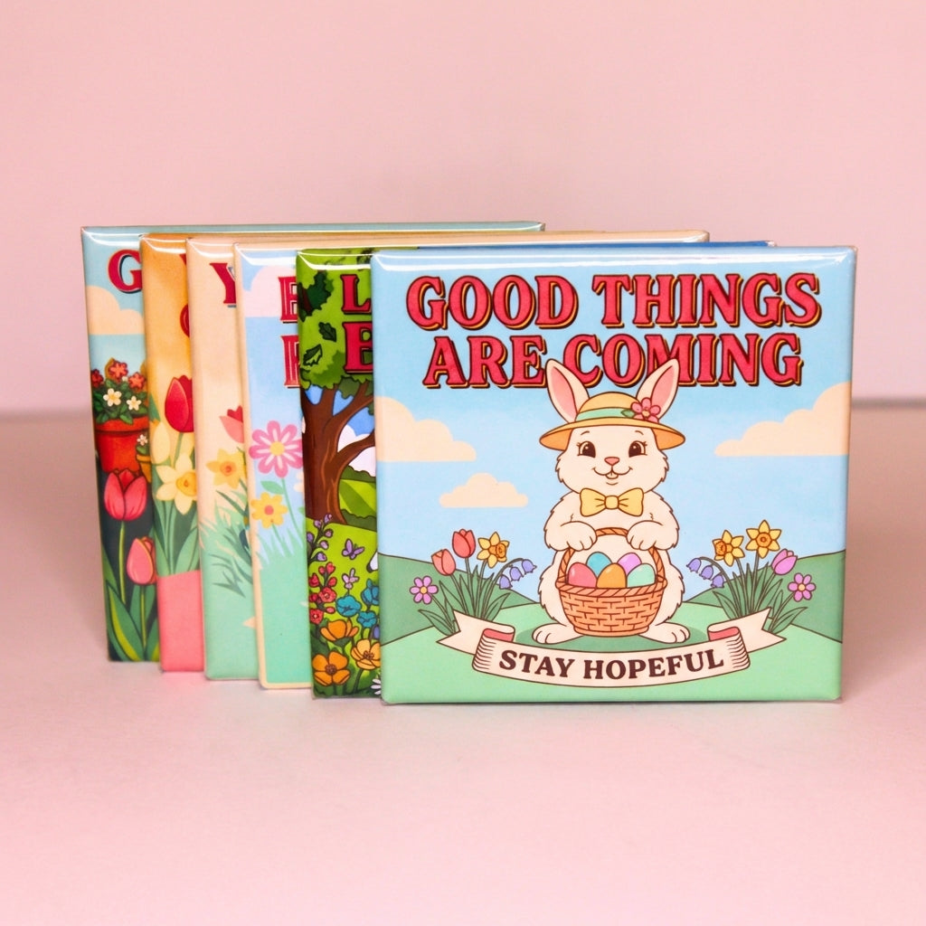 Six Spellbound Magnet Co. Easter 2026 Magnet Pack magnets fanned and stacked upright against a soft pink background, with the Good Things Are Coming / Stay Hopeful design facing forward and the edges of the remaining five designs visible behind it.